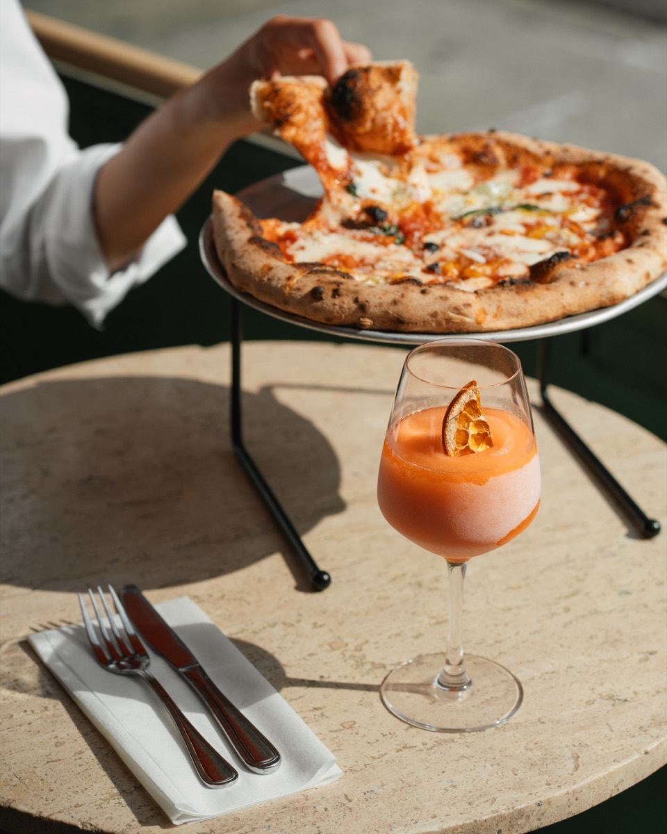 Stone-baked pizza and a frozen Aperol Spritz on an outdoor table at Café Maud